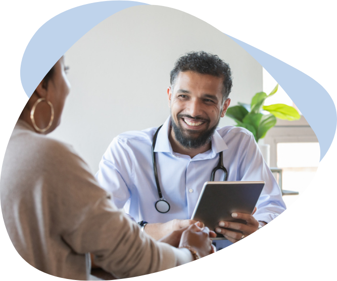 A male doctor holding a tablet and smiling at his patient