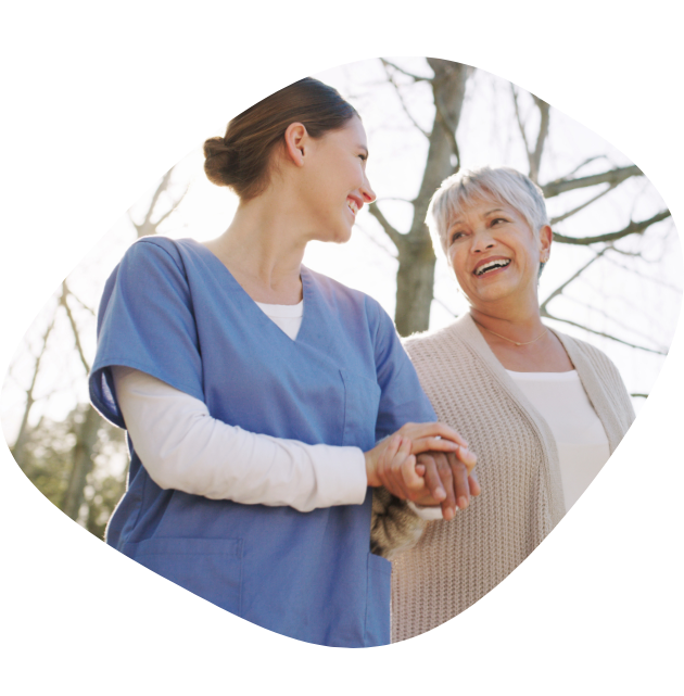 A woman nurse holding her patient's hand and smiling at her during a walk outside