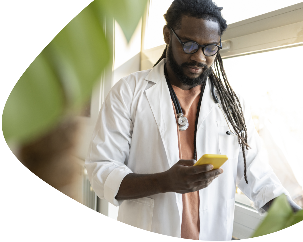 A male healthcare professional standing and looking at his phone