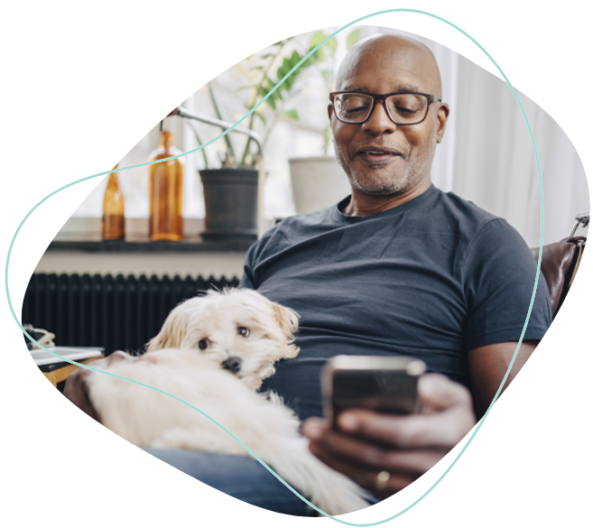 Un homme avec un chien sur ses cuisses qui regarde son téléphone