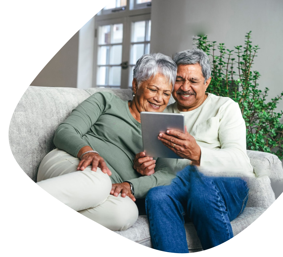 A man and woman sitting on a couch looking at a tablet